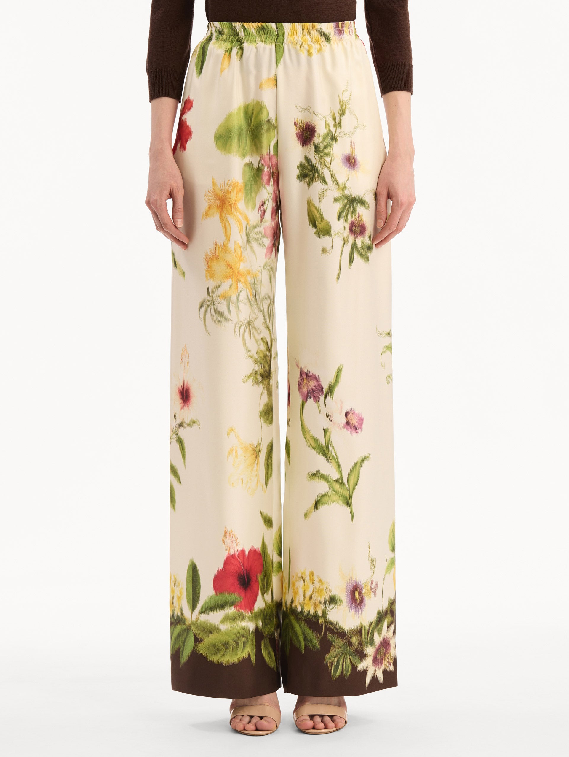 The model is wearing the Dominican Mixed-Floral Wide Leg Pant in ivory printed with an array of Dominican florals. Featuring wide legs and an elastic waistband. Front View.