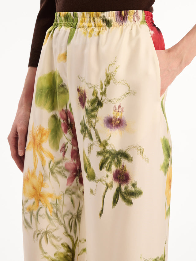 The model is wearing the Dominican Mixed-Floral Wide Leg Pant in ivory printed with an array of Dominican florals. Featuring wide legs and an elastic waistband. Detail View.