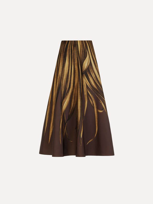 The Palm Leaves Faille Skirt in brown printed with gold palm leaves. Featuring a voluminous, structured silhouette and midi length. Front View.