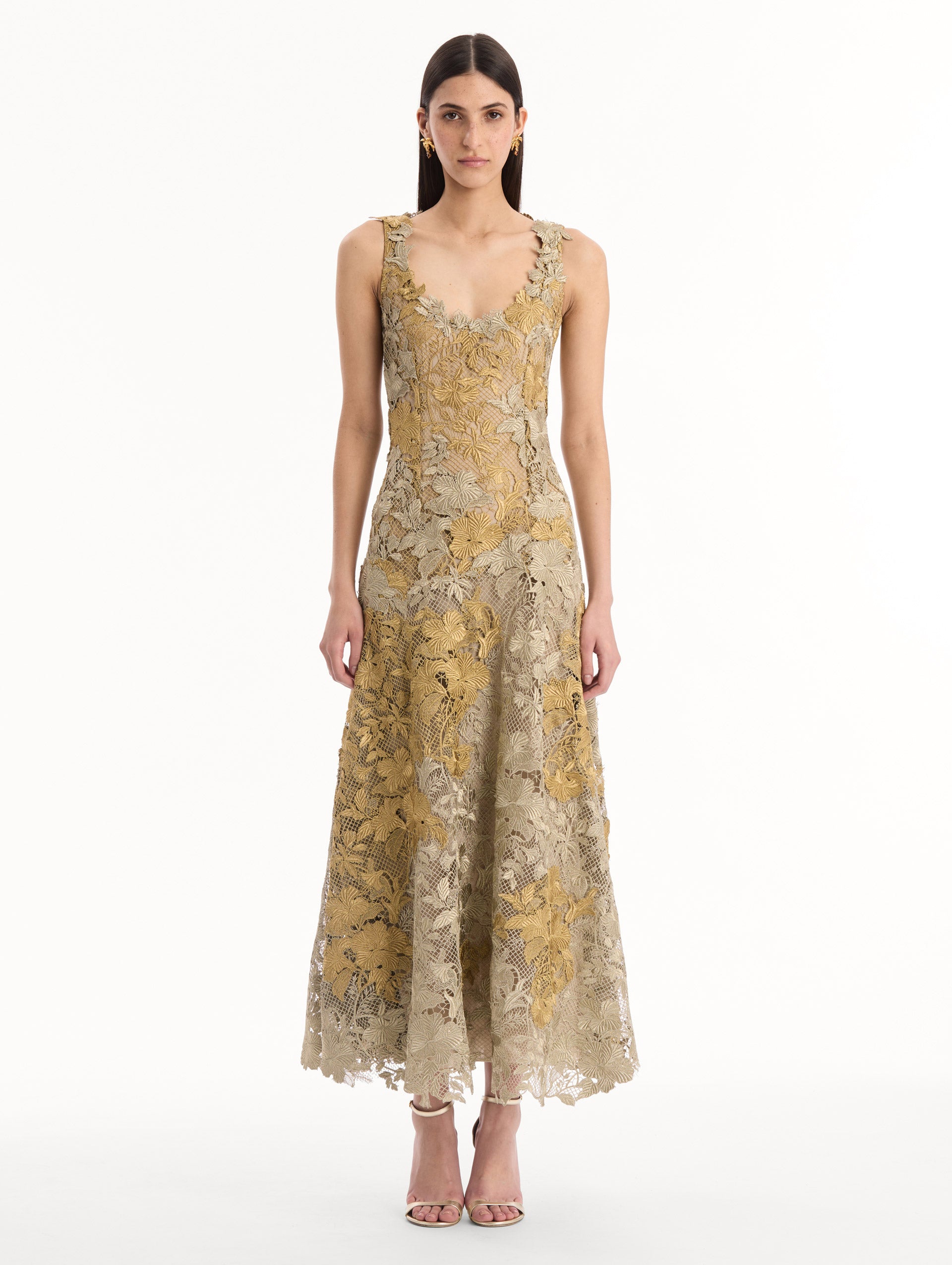 The model is wearing the Hibiscus Metallic Guipure Cocktail Dress in Gold. Featuring metallic guipure lace, a fitted bodice, and softly flared skirt. Front View.