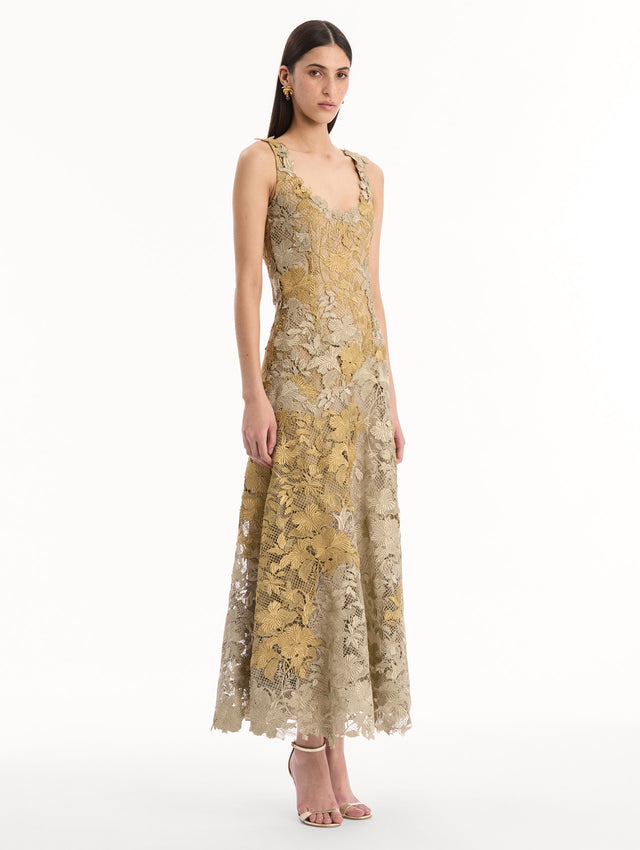 The model is wearing the Hibiscus Metallic Guipure Cocktail Dress in Gold. Featuring metallic guipure lace, a fitted bodice, and softly flared skirt. Side View.