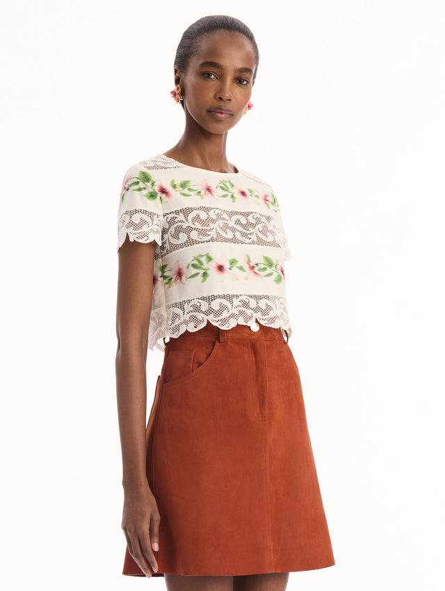The model is wearing the chiné hibiscus striped cotton poplin blouse with guipure lace panels and a striped floral pattern in the color ivory. Side view.