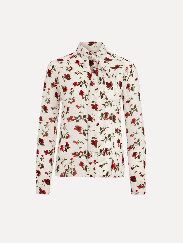 The Hibiscus Silk Chiffon Blouse in white printed with red hibiscus florals. Featuring a tie at neckline, long sleeves, and tailored silhouette. Front View.