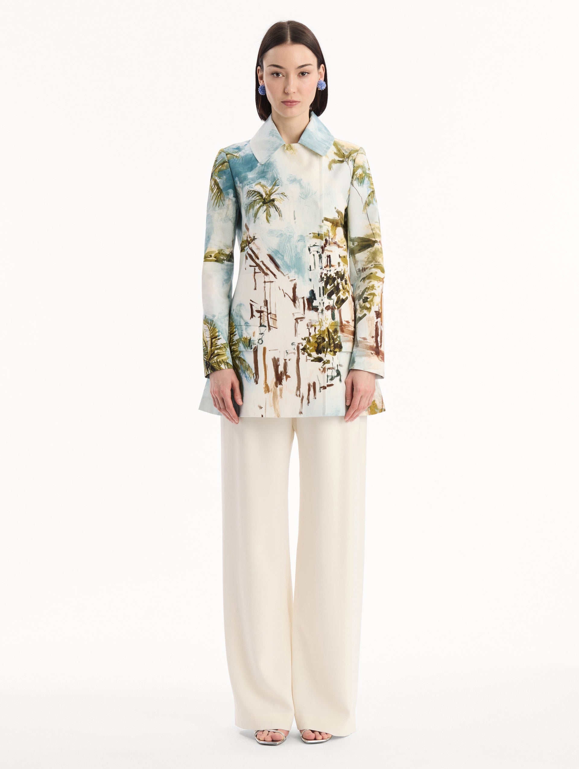 The model is wearing the Dominican Landscape Cotton Poplin Coat featuring an exaggerated collar, hidden buttons, front-flap pockets, and long sleeves. Front View.
