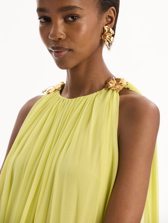 The model is wearing the Hibiscus-Detail Silk Chiffon Caftan in a light yellow-green color. Featuring a draping, gathered silhouette, long skirt, and sculptural hibiscus details at the shoulders. Detail View.