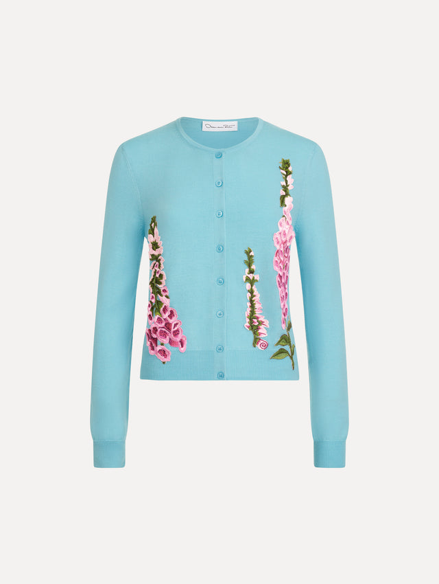 The Foxglove Threadwork Cardigan in vibrant light blue color with floral embroidery and buttons along the center. Front View.