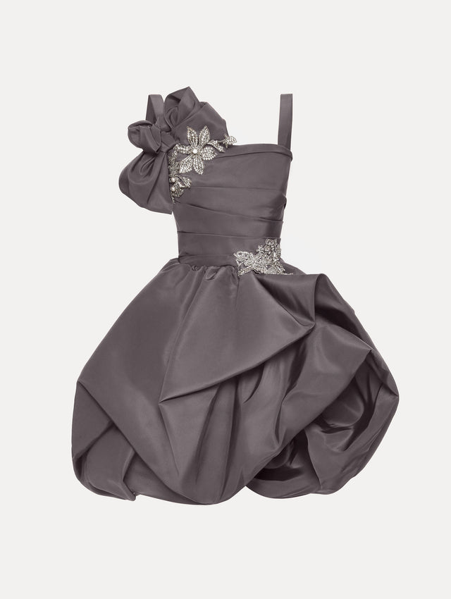 The Brooch Embroidered Cocktail Sleeveless Dress in a dark, grey stone color with a jeweled brooch motif, oversized shoulder bow and voluminous draped skirt.