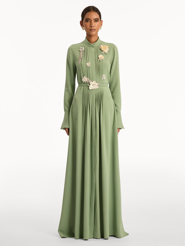 Green Brooch Embroidered Long Sleeve Caftan featuring pleated front detailing, high neckline, and floral appliqué embellishments at the bodice and waist. Front View.
