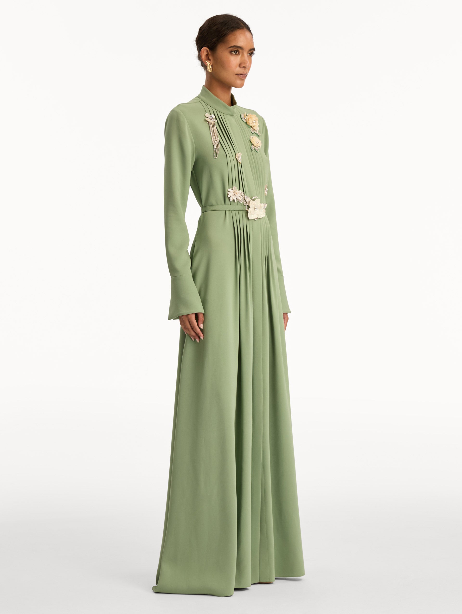 Green Brooch Embroidered Long Sleeve Caftan featuring pleated front detailing, high neckline, and floral appliqué embellishments at the bodice and waist. Side View.