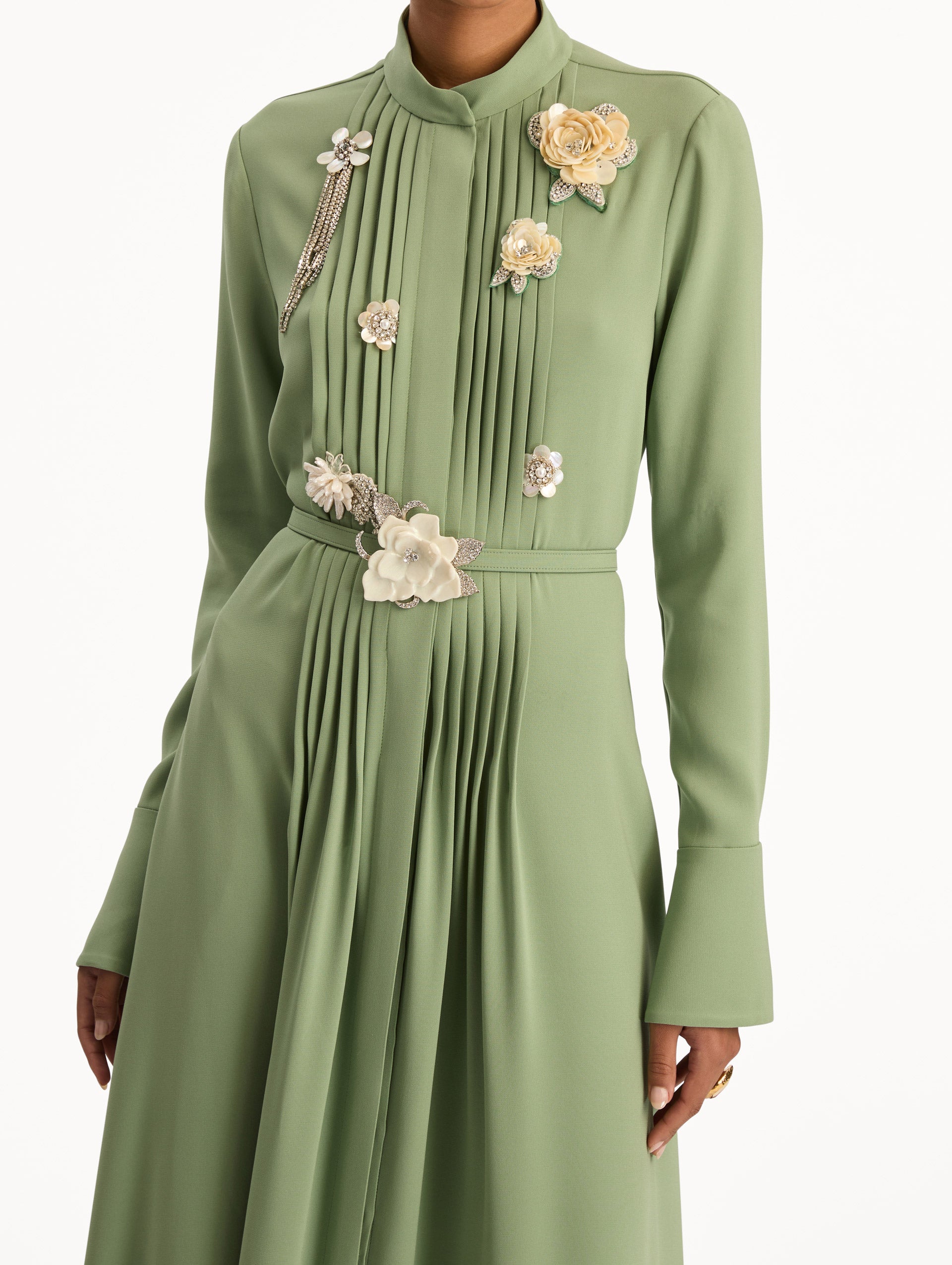 Green Brooch Embroidered Long Sleeve Caftan featuring pleated front detailing, high neckline, and floral appliqué embellishments at the bodice and waist. Zoom View.