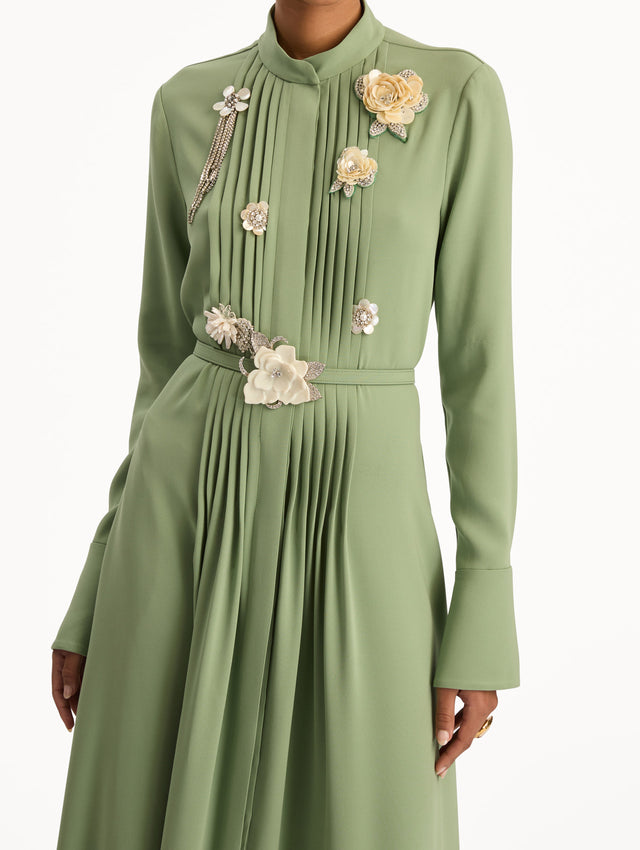 Green Brooch Embroidered Long Sleeve Caftan featuring pleated front detailing, high neckline, and floral appliqué embellishments at the bodice and waist. Zoom View.