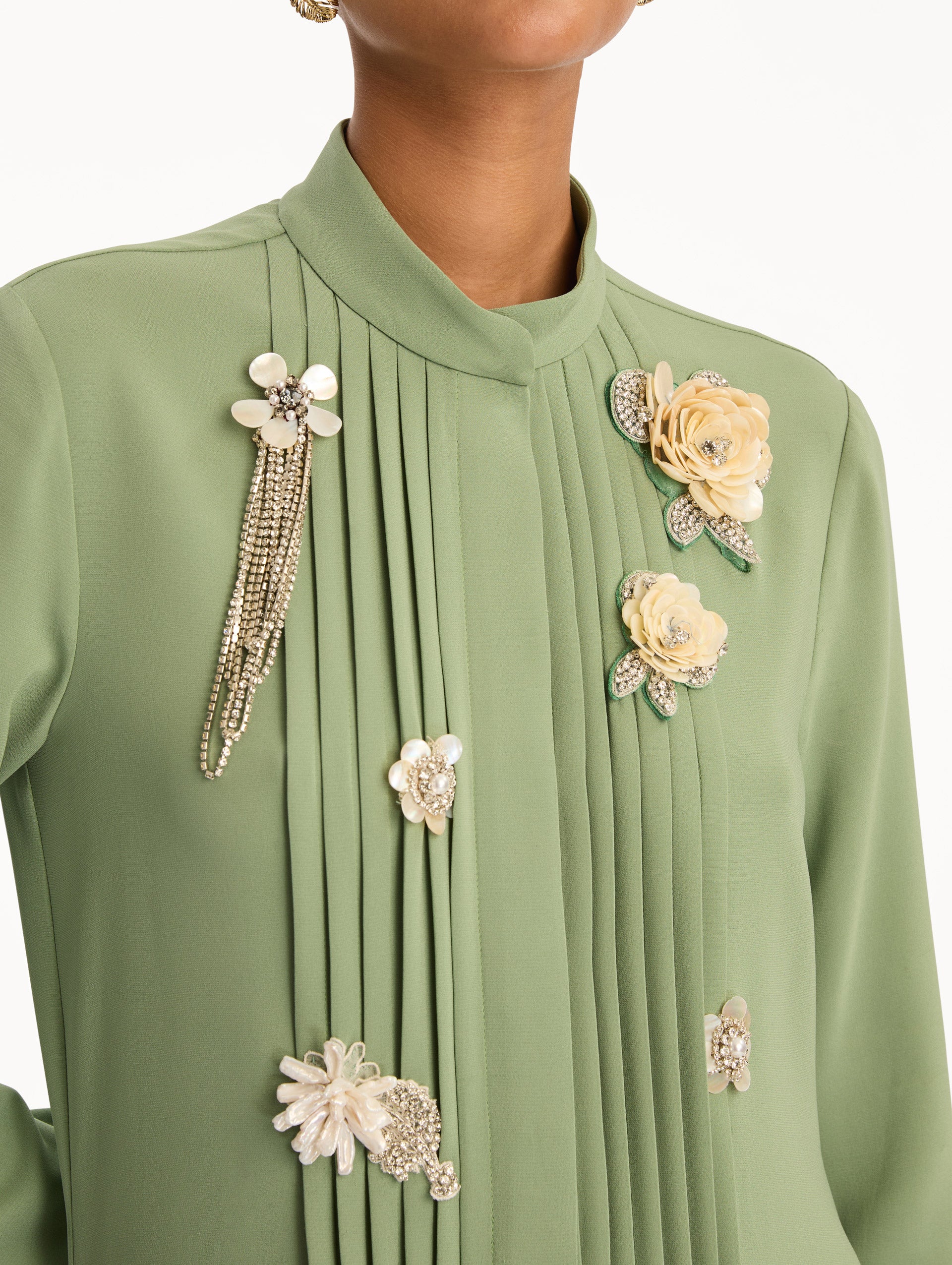 Green Brooch Embroidered Long Sleeve Caftan featuring pleated front detailing, high neckline, and floral appliqué embellishments at the bodice and waist. Zoom View.