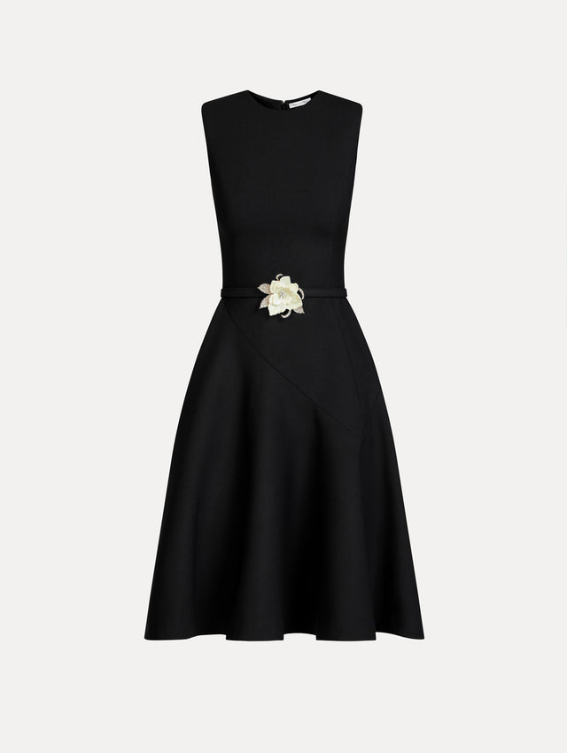 Black Floral Belt Sleeveless Dress featuring a belted waist with a white floral embellishment and a knee-length skirt. Front View.