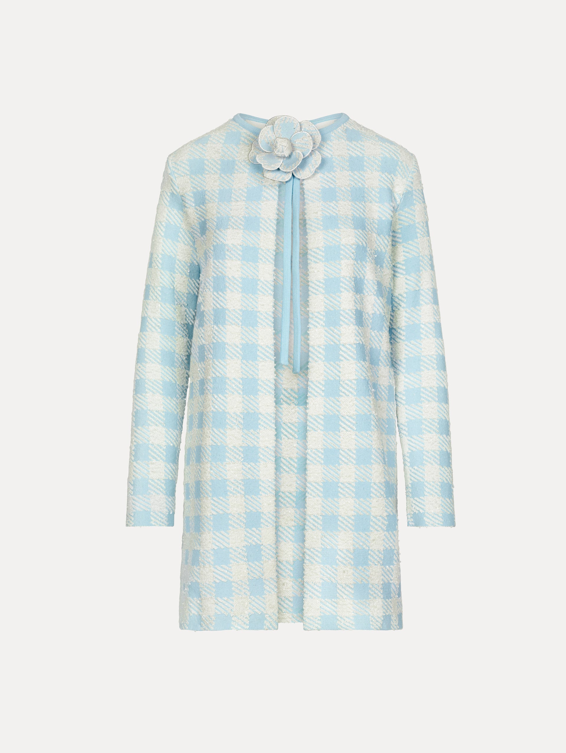 Coat in the colors light blue and white gingham print, featuring a flower emblem in the neckline center and long sleeves.