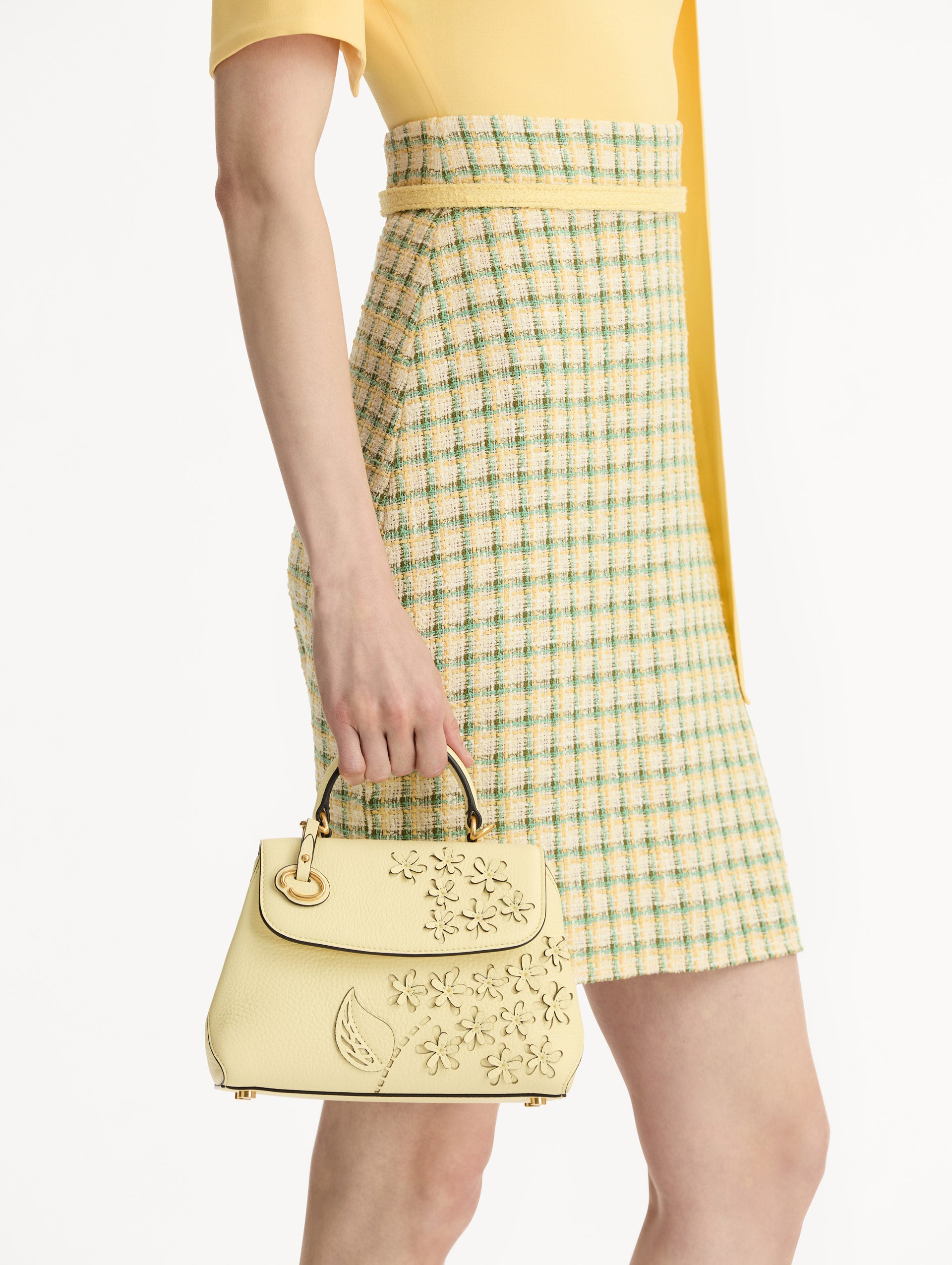 The Mini Poppy in yellow with floral cutout designs and gold hardware. Front View. 