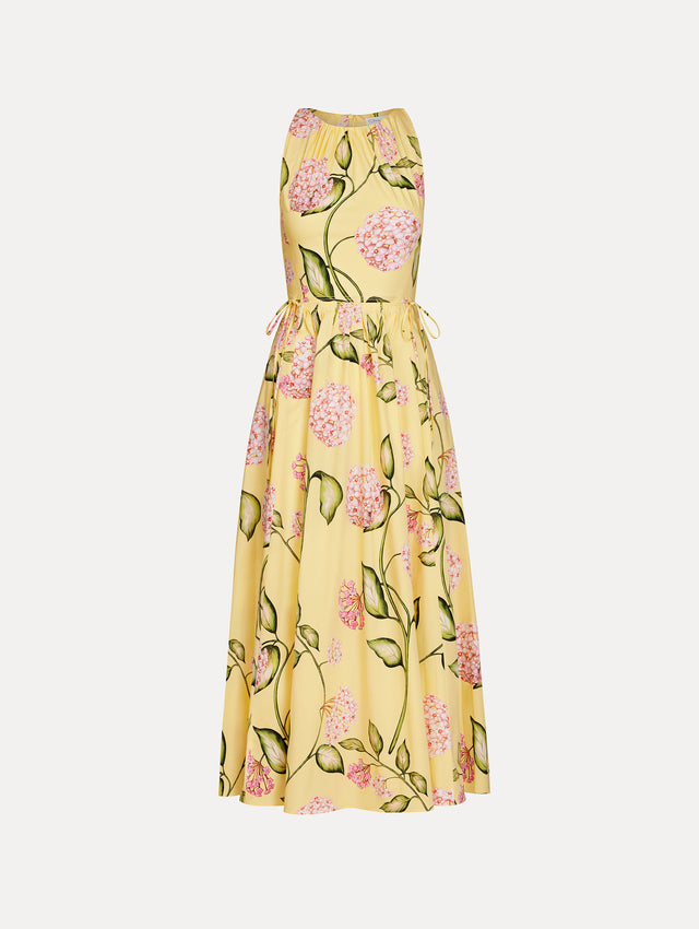 Halter neck, sleeveless, cotton poplin midi dress in yellow. Pleated with vivid pink flower print. Subtle bows at waist. Front View.
