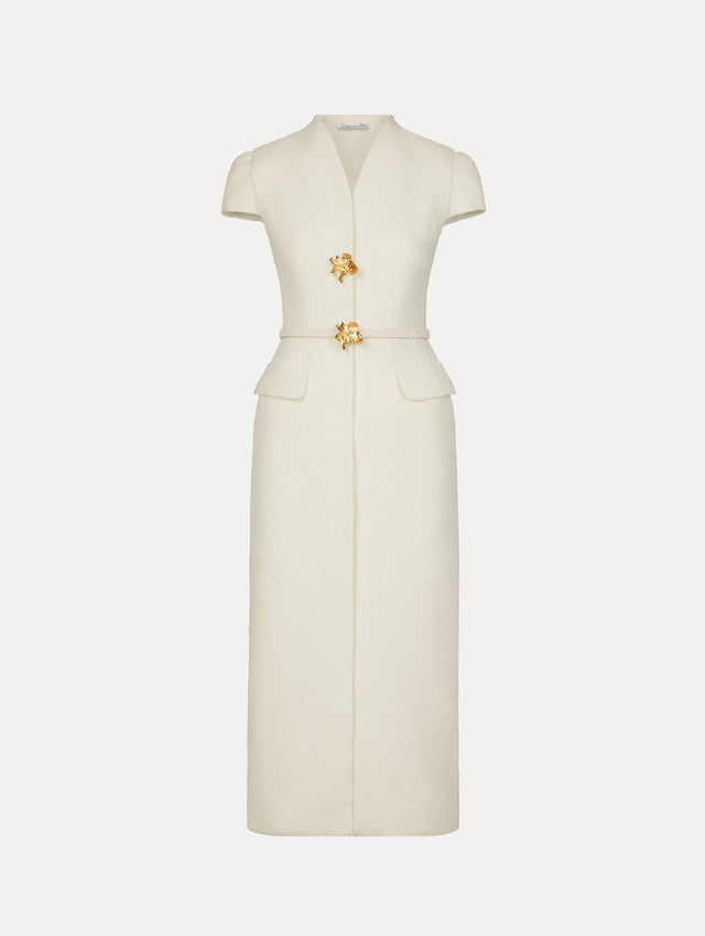 Tailored dress in the color white with cap sleeve, front flap pockets, matching belt at waist, and gold flower button front.