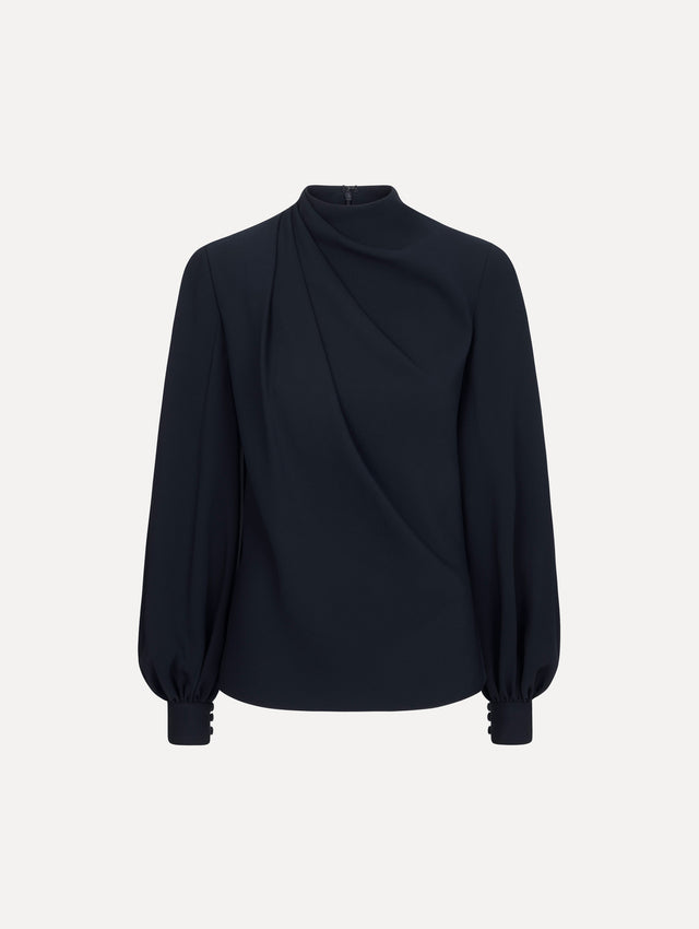The model is wearing the Draped Georgette Blouse in the color Navy. Featuring silk georgette, a draping mock-neckline, and long, billowed sleeves. Front View.