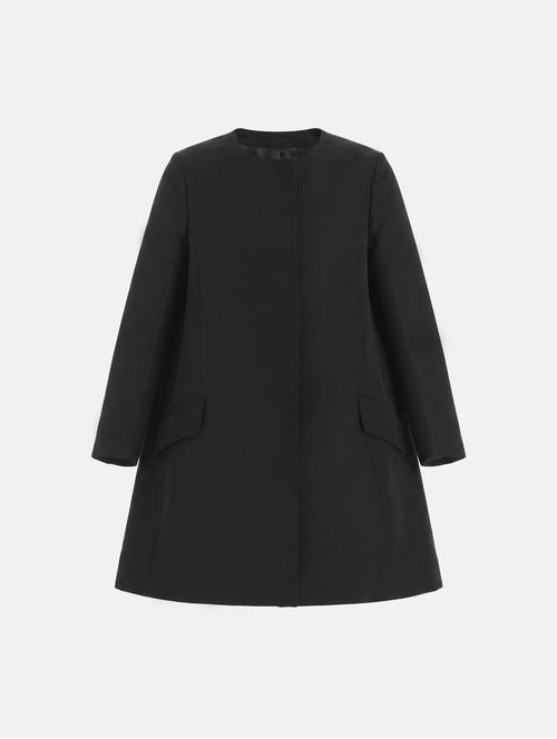 The model is wearing the Silk Faille Short Coat with flap pockets in the color black. 