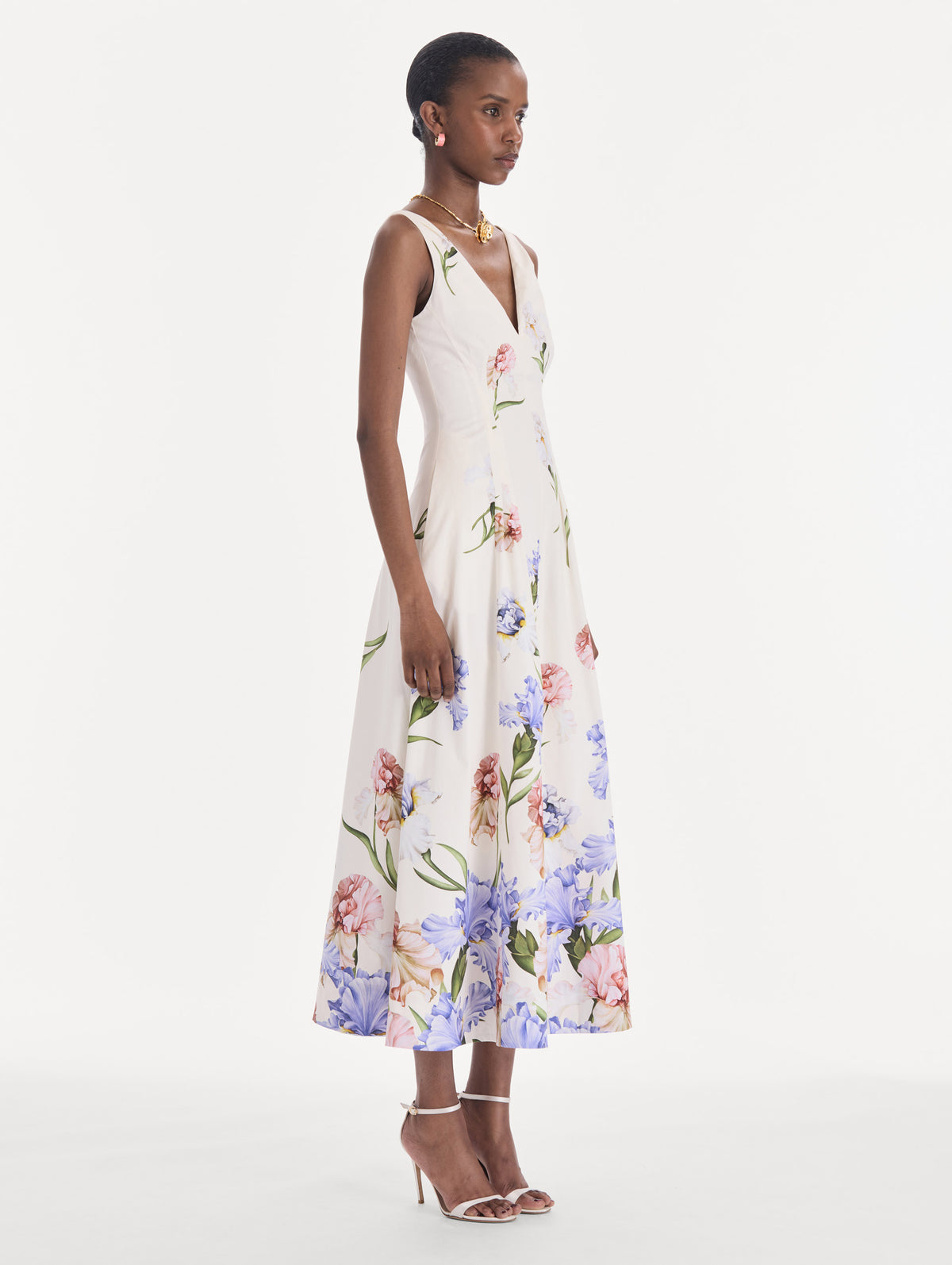 The model is wearing a sleeveless V-neck large iris degrade poplin dress. Side view.