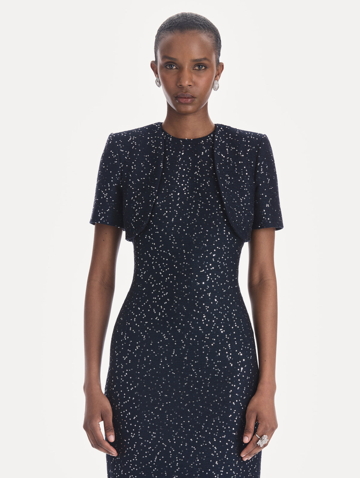 The model is wearing a short sleeve sequin tweed cape. Front view.
