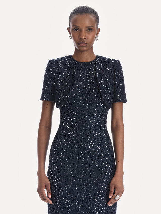 The model is wearing a short sleeve sequin tweed cape. Front view.