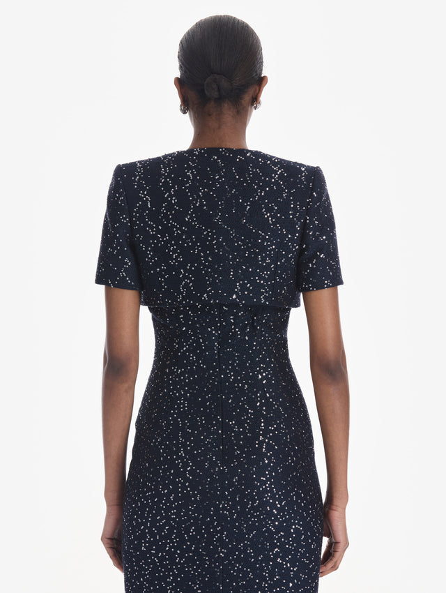 The model is wearing a short sleeve sequin tweed cape. Side view.