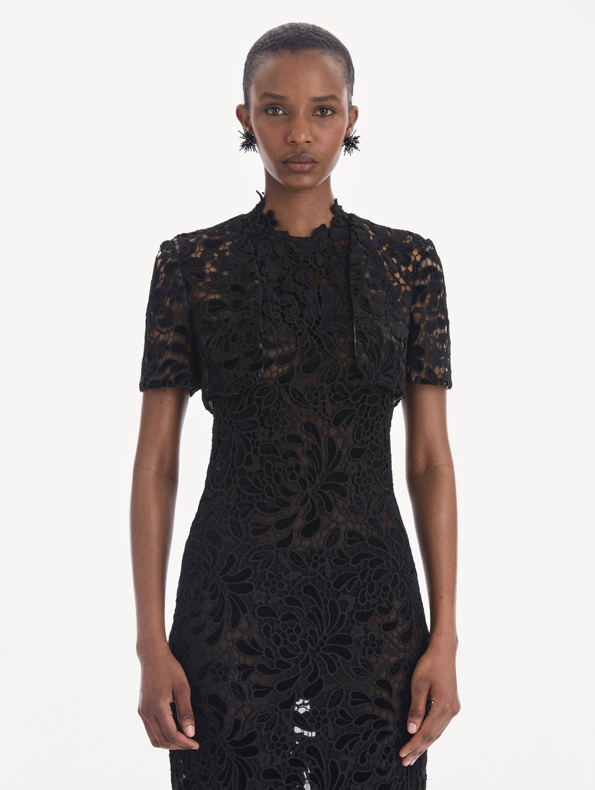 The model is wearing a short sleeve cape. Front view.