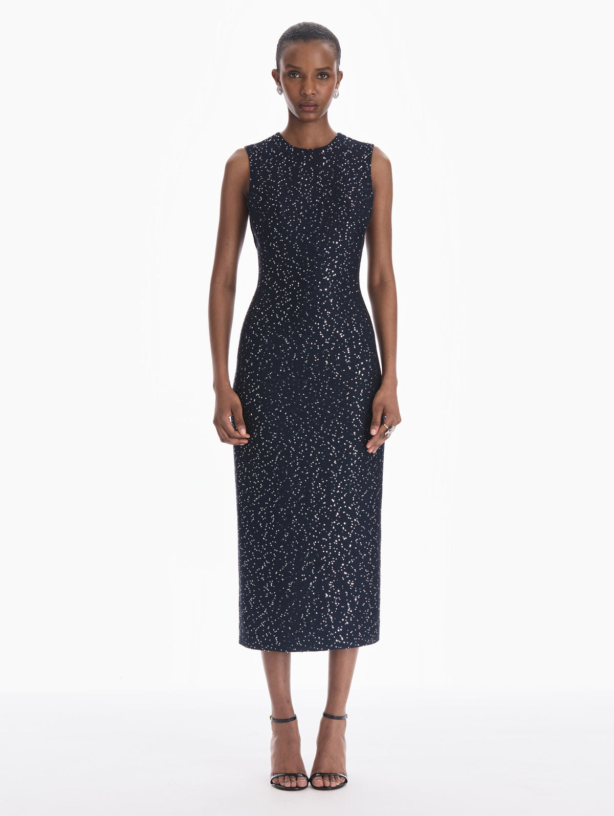 The model is wearing a sleeveless sequin tweed cocktail dress in navy. Front view.