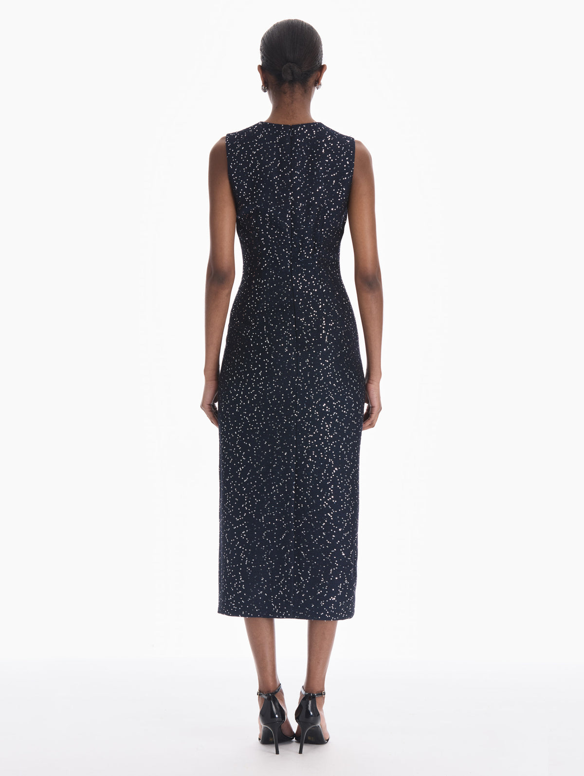 The model is wearing a sleeveless sequin tweed cocktail dress in navy. Back view.