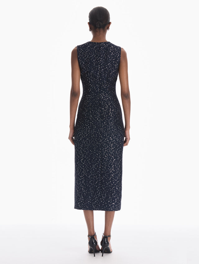 The model is wearing a sleeveless sequin tweed cocktail dress in navy. Back view.