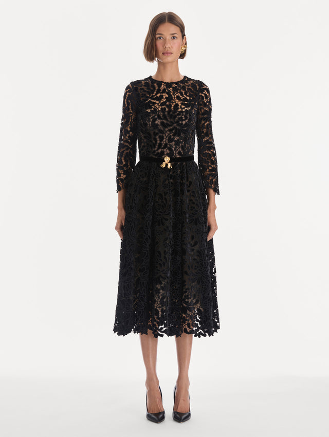 The model is wearing a long sleeve chrysanthemum guipure cocktail dress. Front view.
