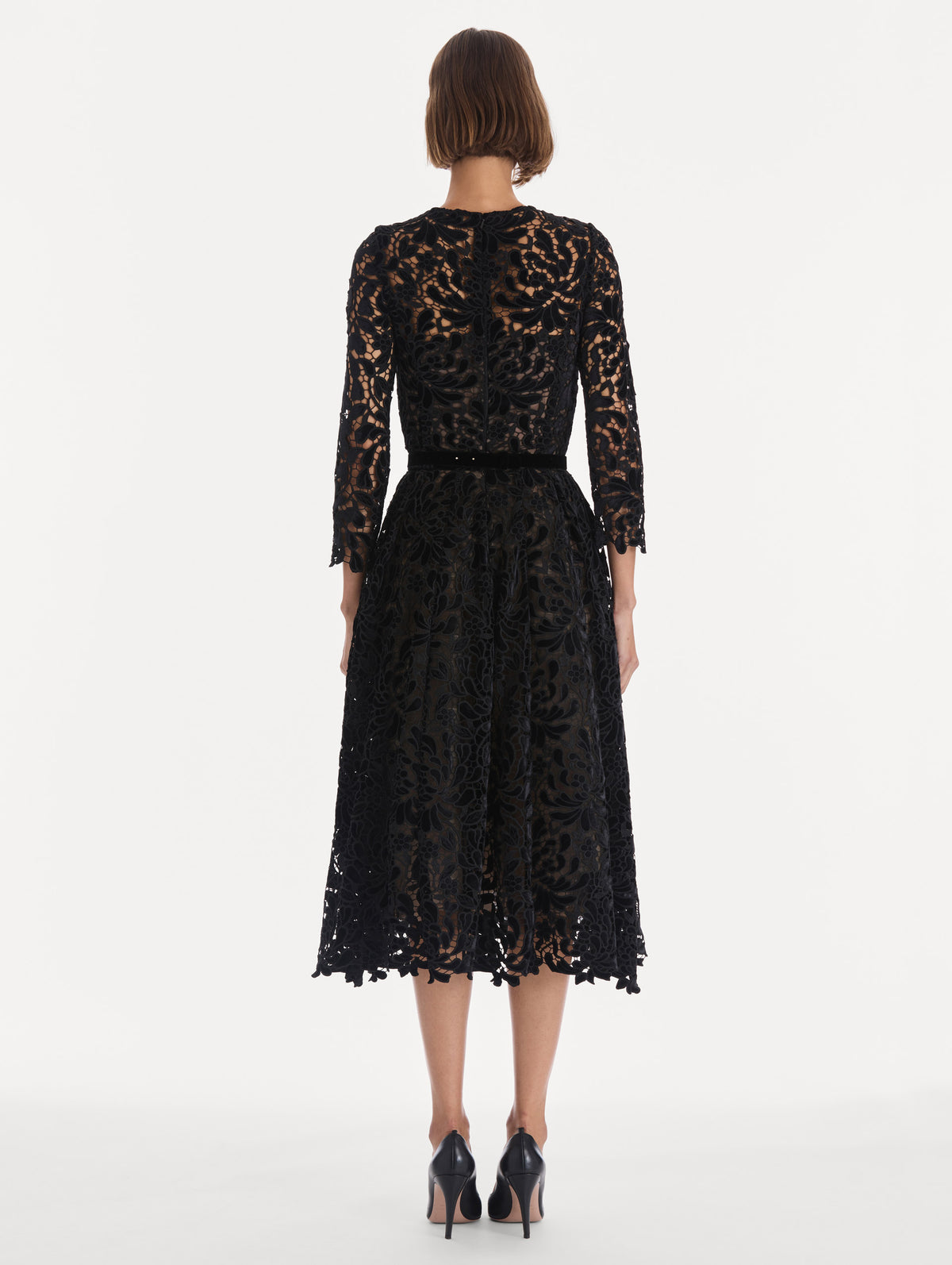 The model is wearing a long sleeve chrysanthemum guipure cocktail dress. Back view.