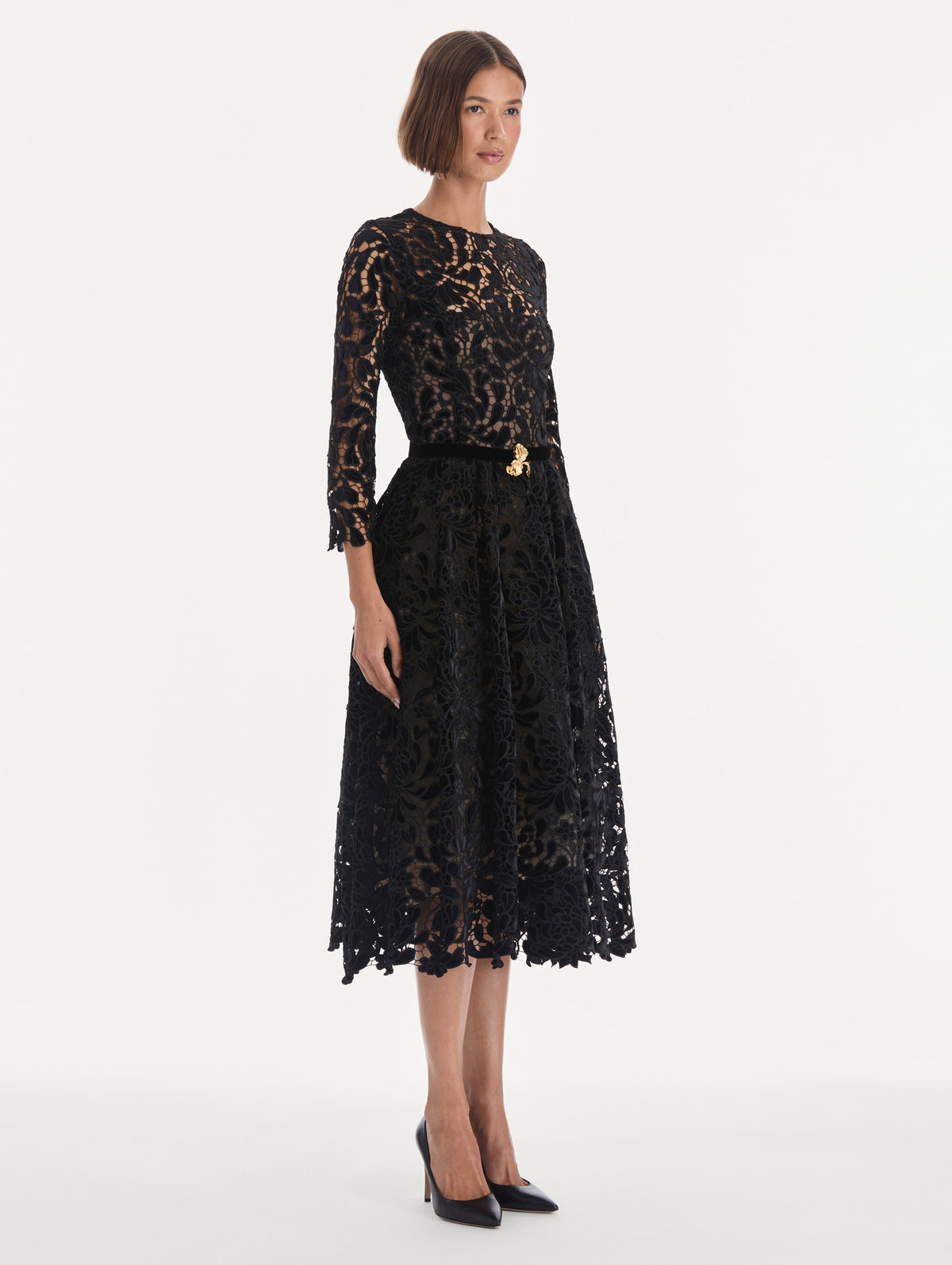 The model is wearing a long sleeve chrysanthemum guipure cocktail dress. Side view.