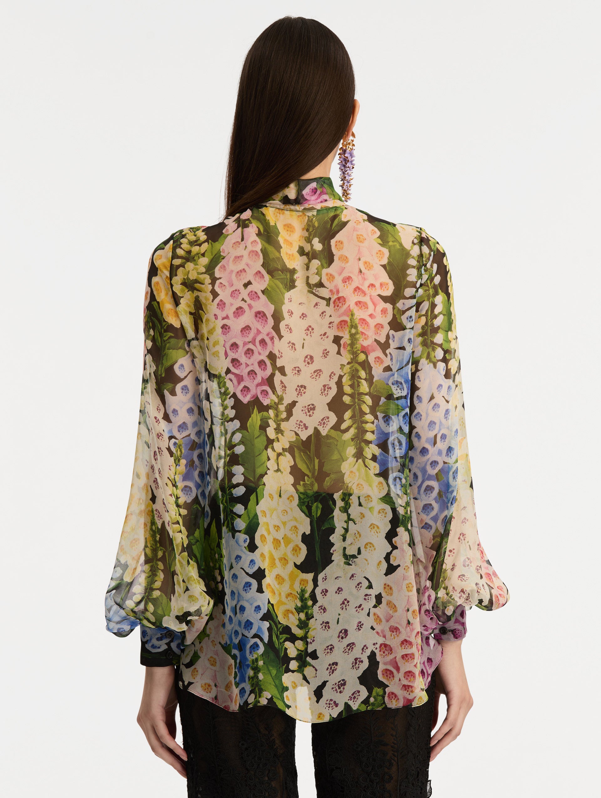 Black and floral Foxglove Tie-Neck Chiffon Blouse with billowing long sleeves with cuffed wrists. Back View.