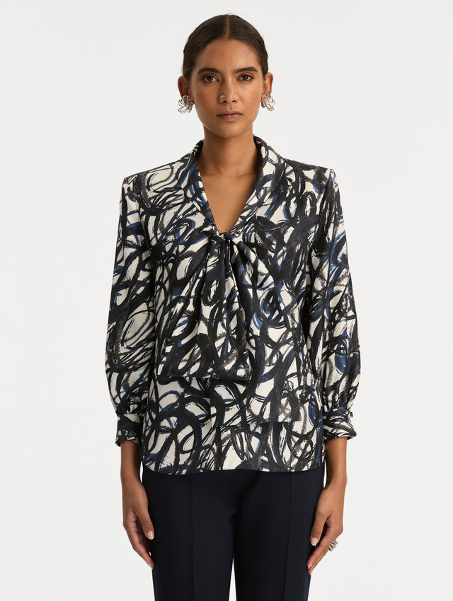 White and Blue Abstract Sketch Silk Twill Blouse featuring a deep V-neckline with knotted drape detail and long sleeves. Front View.