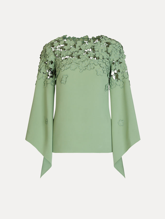 The Floral Appliqué Lattice Blouse in green featuring a floral, open lattice neckline and long, flowy sleeves. Front View.
