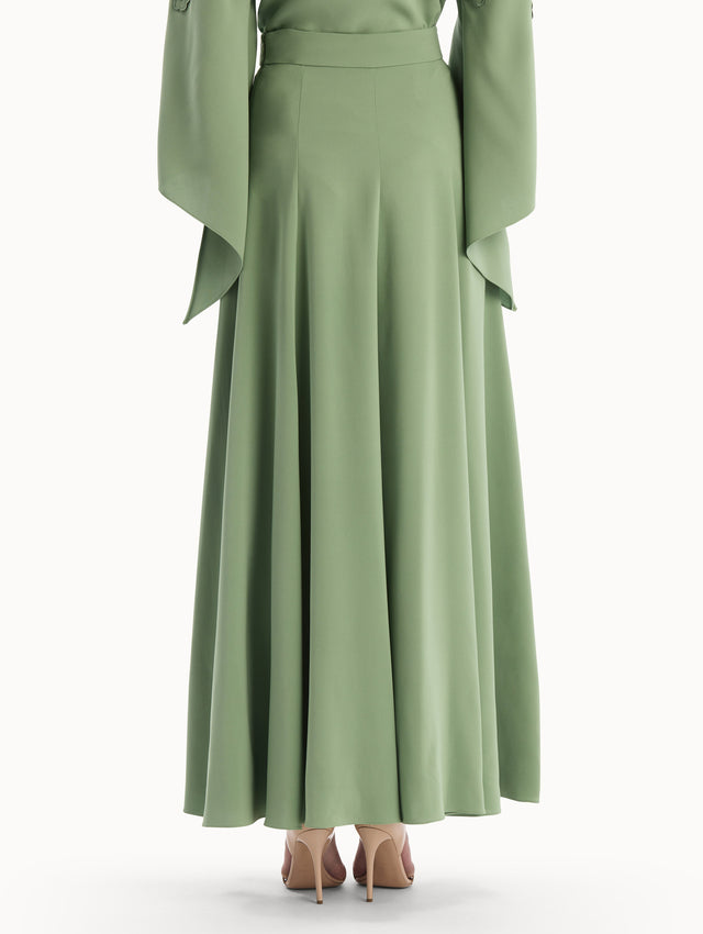 The model is wearing the Silk Georgette Midi Skirt in the color green featuring a high-waist and classic, flowing skirt. Back View.