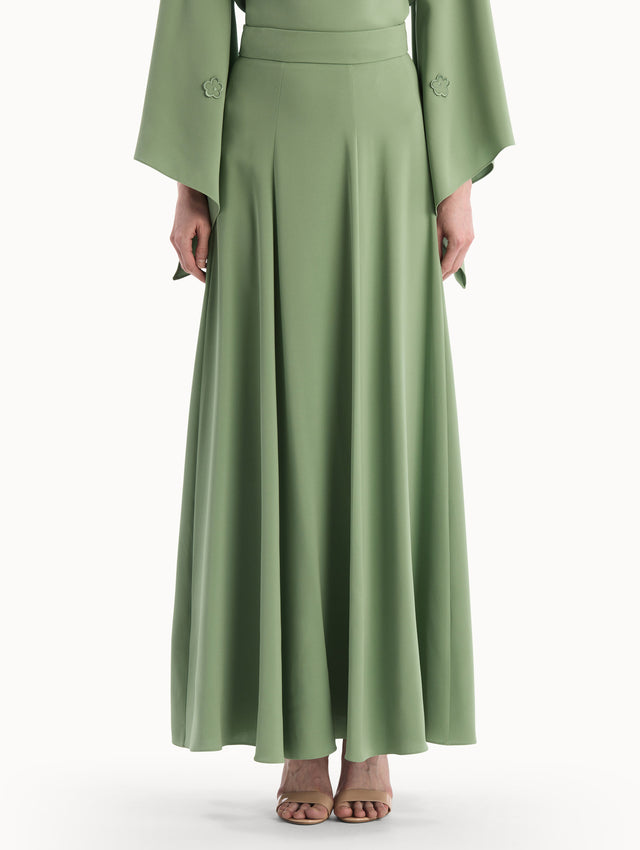 The model is wearing the Silk Georgette Midi Skirt in the color green featuring a high-waist and classic, flowing skirt. Front View.