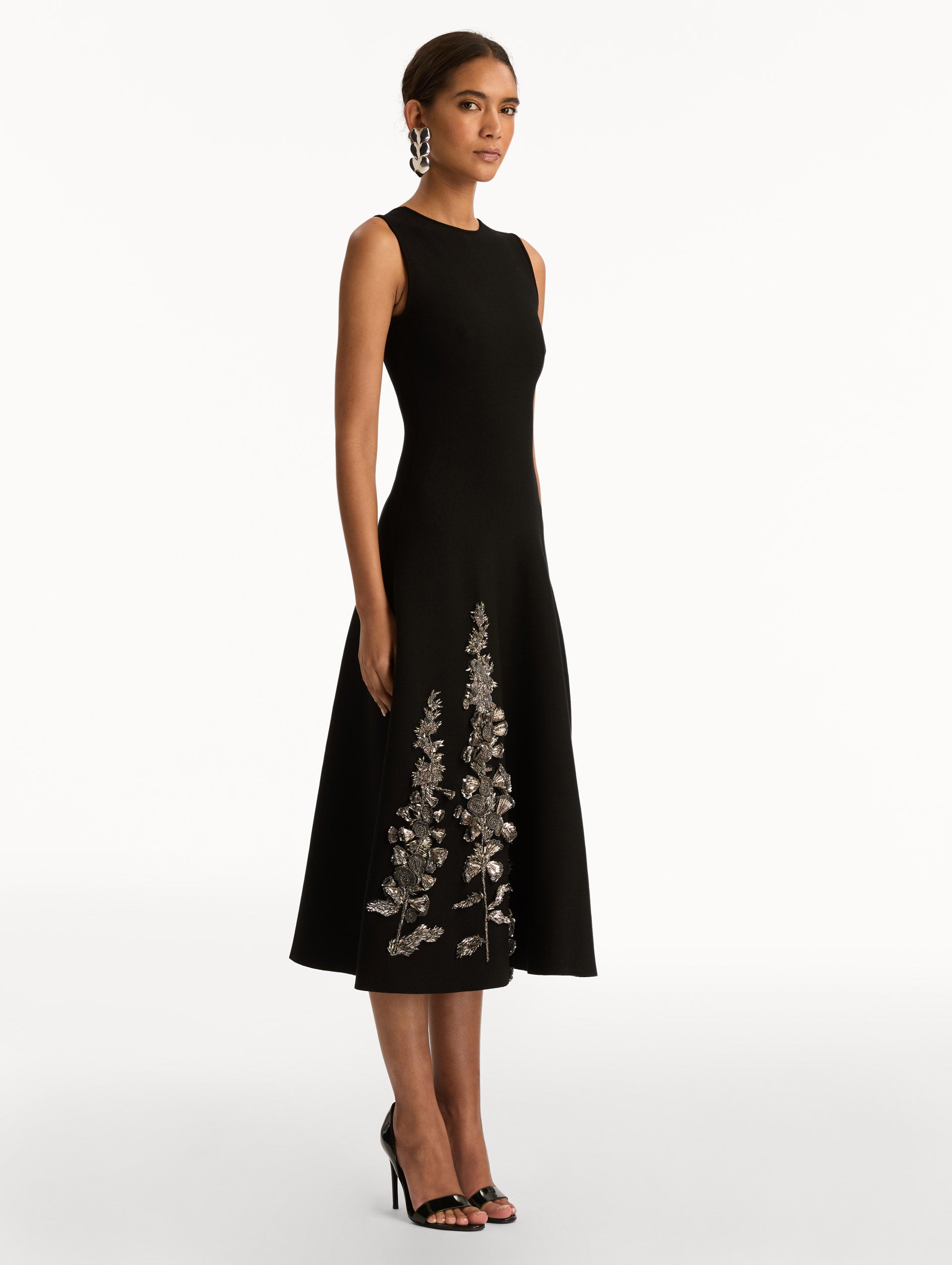 Black Foxglove Sequin Embroidered Knit Dress featuring a round neckline and silver floral embroidery along the skirt. Side View.