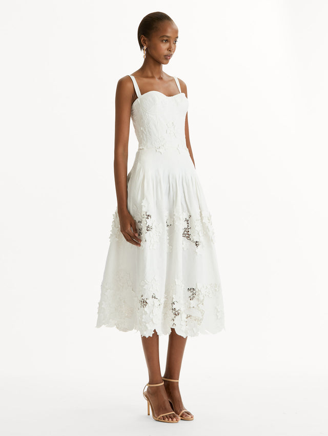 Cotton stretch twill dress. Sculpted bustier bodice with full, midi-length skirt.  porcelain-flower guipure lace along hem. Three-dimensional floral appliqués in layered white-on-white texture. Side View.