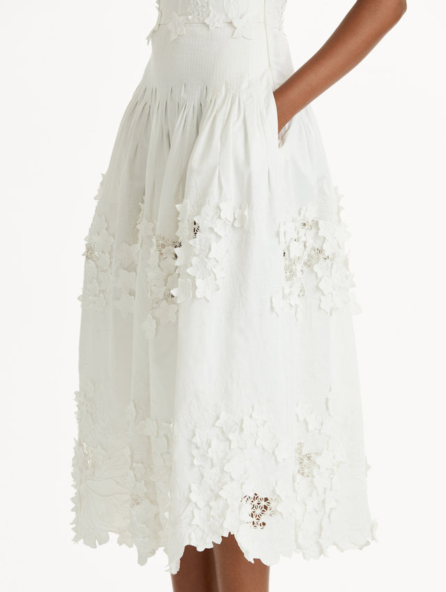 Cotton stretch twill dress. Sculpted bustier bodice with full, midi-length skirt.  porcelain-flower guipure lace along hem. Three-dimensional floral appliqués in layered white-on-white texture. Side View, Close Up.
