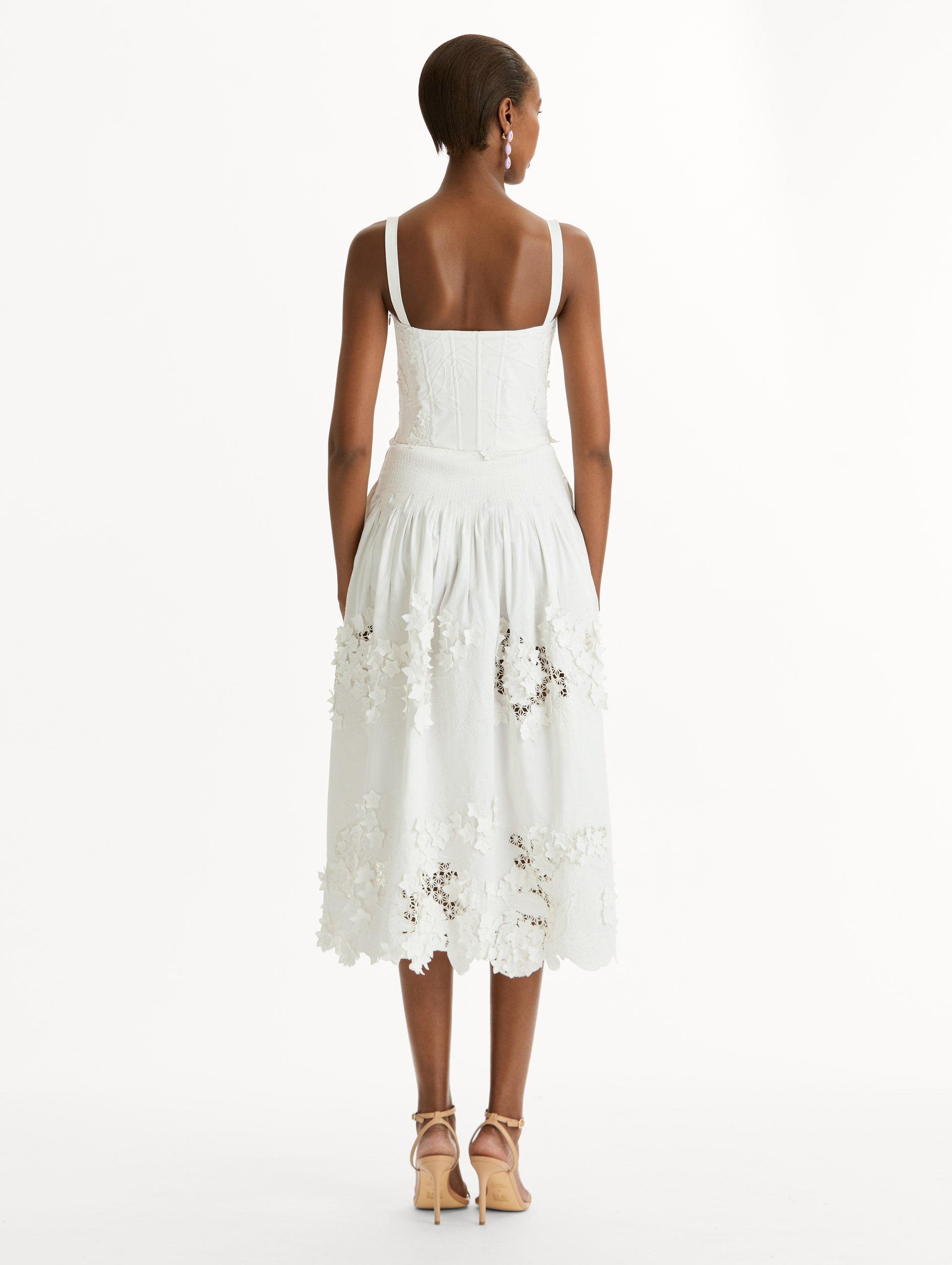 Cotton stretch twill dress. Sculpted bustier bodice with full, midi-length skirt.  porcelain-flower guipure lace along hem. Three-dimensional floral appliqués in layered white-on-white texture. Back View.