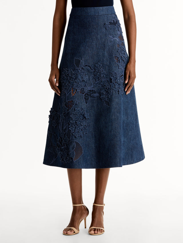 High waisted denim skirt with intricate porcelain flower threadwork. Classic A-line silhouette. Mid length. Front View. 