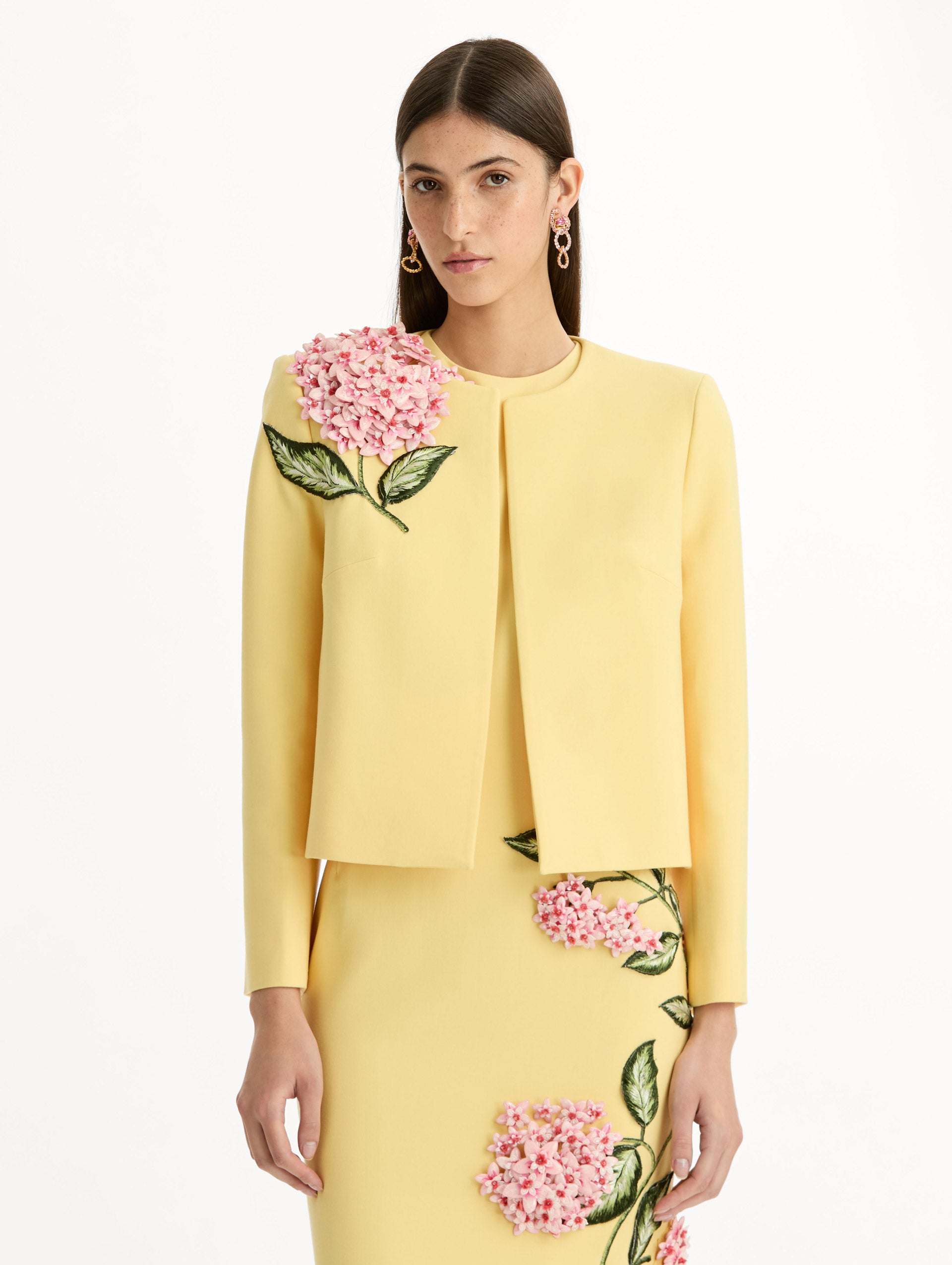Cropped yellow jacket tailored from double-faced stretch wool and finished with sculptural porcelain flower embroidery at the shoulder. Front View.