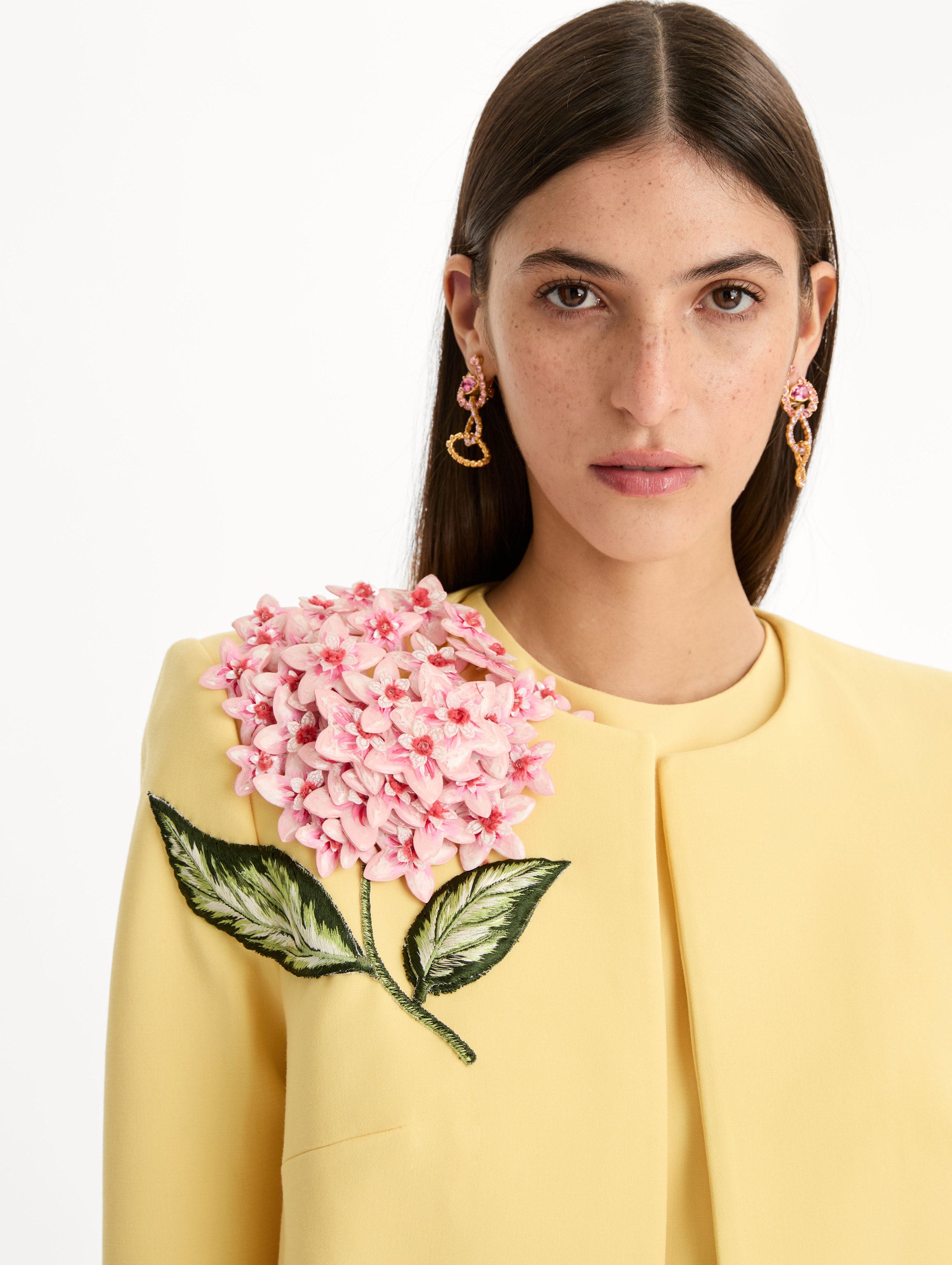 Cropped yellow jacket tailored from double-faced stretch wool and finished with sculptural porcelain flower embroidery at the shoulder. Front View, Close Up.