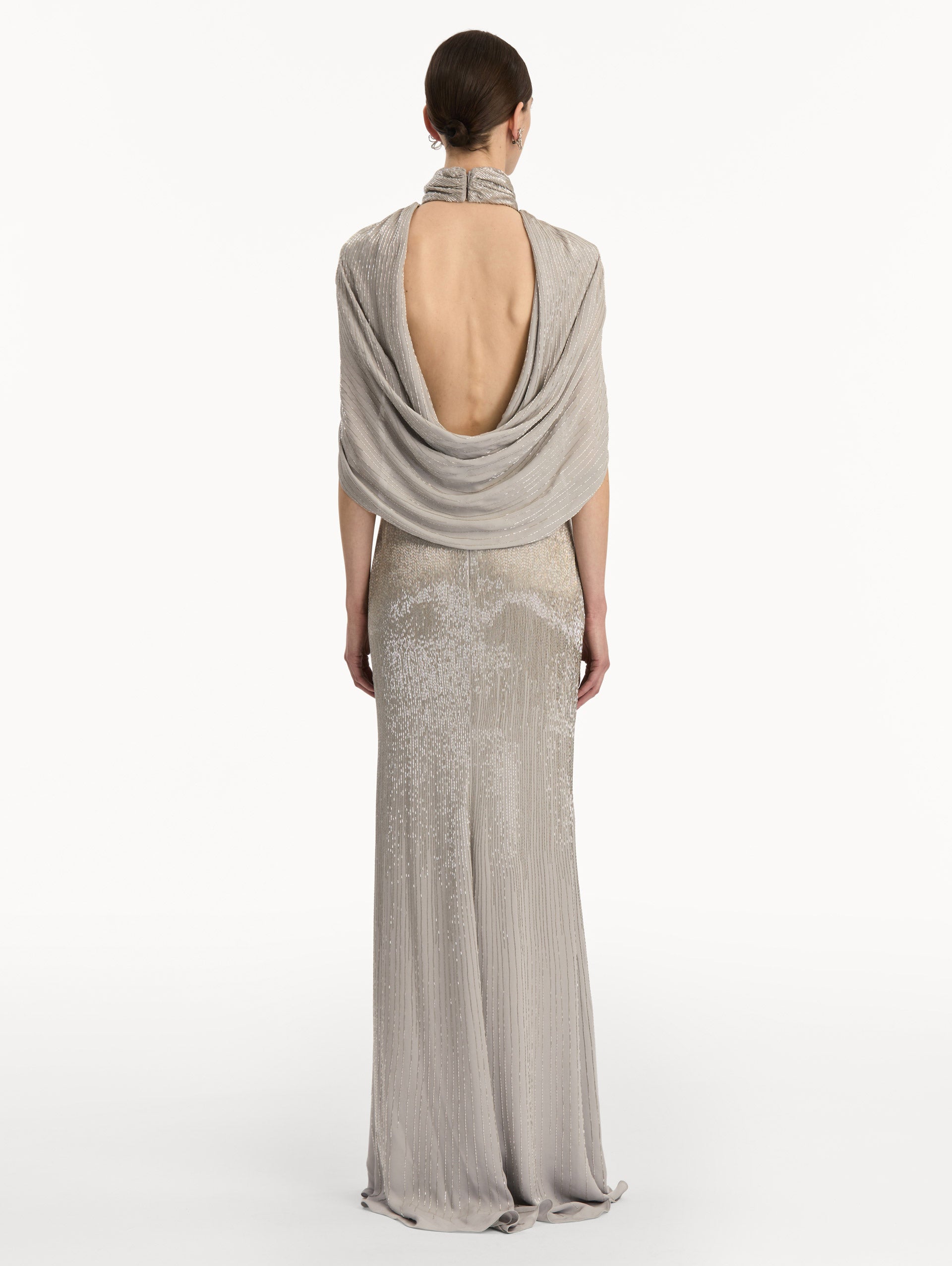 Silver Bugle Bead Lamé Draped Gown with a high neckline, draped cape sleeves, and metallic finish. Back View.