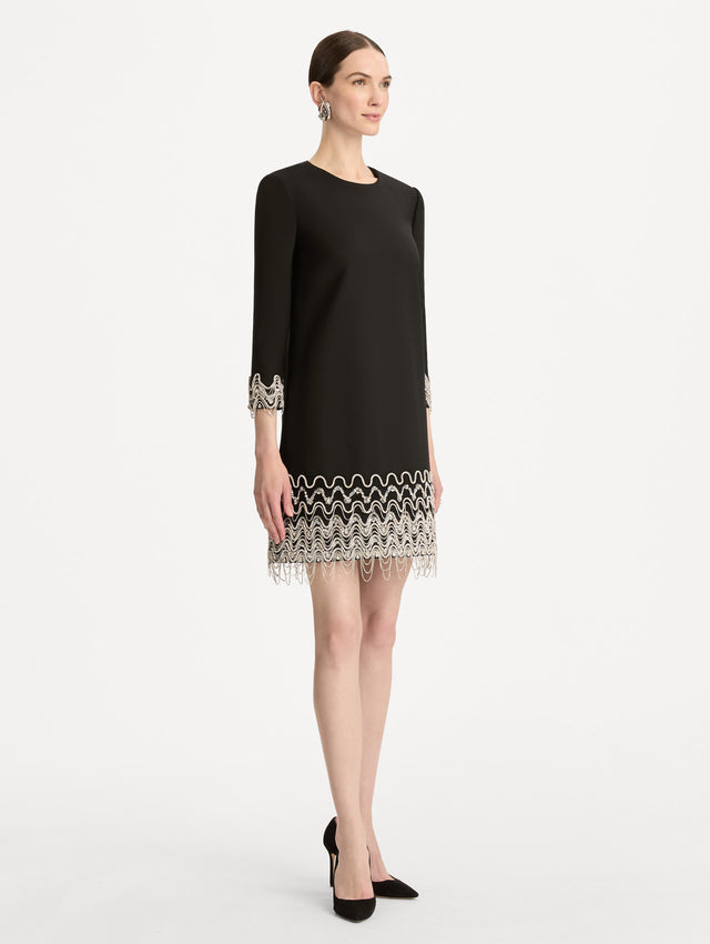 Black Crystal Wave Embroidered Shift Dress with long sleeves and beaded embellishments along the hemline and sleeve cuffs. Side View.