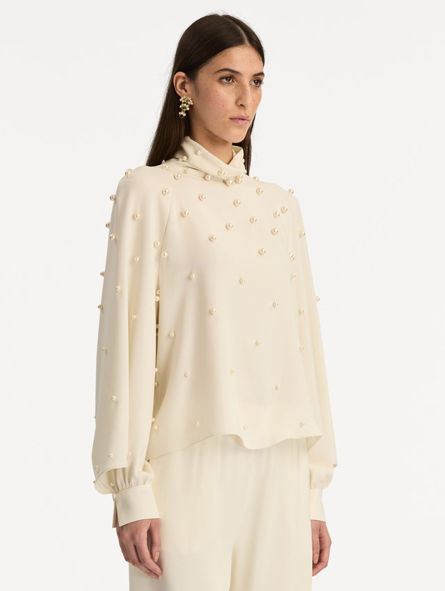 Ivory Pearl Cluster Georgette Blouse with long puff sleeves, a high neck, and pearl embellishments throughout. Side View.