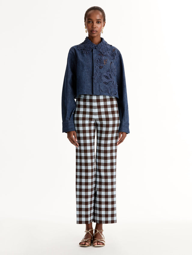 Cropped denim jacket with intricate porcelain flower threadwork and cutout detailing across the front and collar. Long sleeve. Front View.